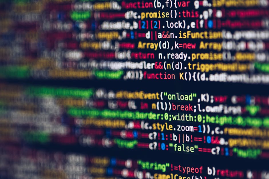 A close-up view of a computer screen displaying lines of colorful programming code, with syntax highlighting in red, green, blue, yellow, and white on a dark background. The text includes various code