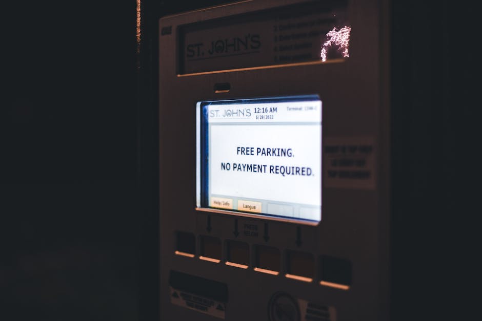Close-up of a digital parking meter with a backlit screen displaying the message 'FREE PARKING. NO PAYMENT REQUIRED.' in black text on a white background. The meter has a rectangular shape with a whit